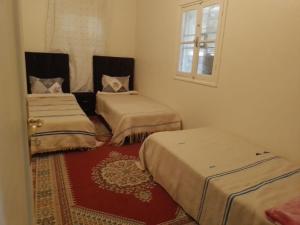 three beds in a room with a window at Gite Tilouguite in Tillouguit nʼAït Isha