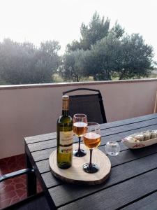 a bottle of wine and two glasses on a wooden table at Vacation Home Katarina in Nin