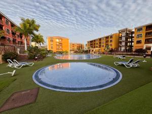 a large pool in a courtyard with chairs and buildings at Alquilaencanarias El Palm Mar in Palm-Mar +9 photos