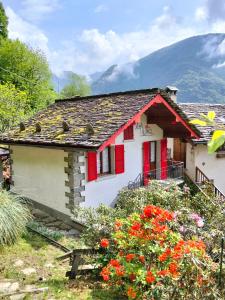 a small white house with red shutters and flowers at La baita alpina in Scopello