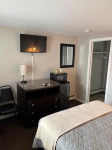 a hotel room with a bed and a dresser and a desk at Shore Point Motel in Point Pleasant Beach
