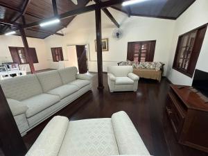 a living room with a white couch and a bed at Casa Bella Itaúna Suites in Saquarema