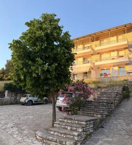 a tree sitting in front of a building at Vila Llaman Luxury Rooms in Himare