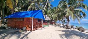 a wooden shack on a beach with palm trees at Cabañas frente al mar Isla de Guna Yala Aroma in Niatupo
