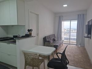 a kitchen and living room with a table and a couch at Flat Itaguai in Itaguaí