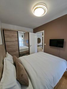 a bedroom with a large white bed and a flat screen tv at Apartman Merry Lux in Vrnjačka Banja