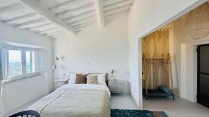 a white bedroom with a bed and a window at SuSuMare in Campiglia Marittima