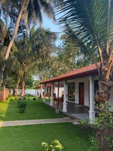 a house with palm trees and a green yard at 108 Palms Beach Resort in Trincomalee