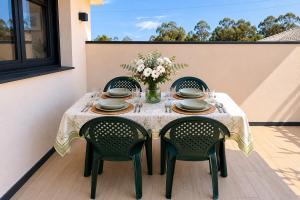 a table with chairs and a vase of flowers on a patio at Casa Muxía Mar y montaña in Muxia
