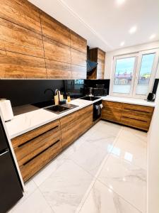 a kitchen with wooden cabinets and a white tile floor at Exclusive Apartament Centrum 45m in Tarnów +14 photos
