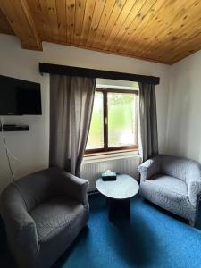 a living room with two couches and a table and a window at Hideout Villa in Hazlov
