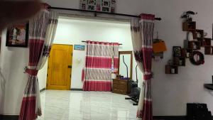 a living room with red and white curtains and a door at Apex inn in Manippai