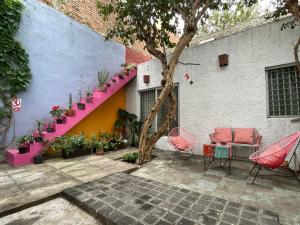a patio with pink chairs and a table and a building at El Pinche Hostal in Guadalajara
