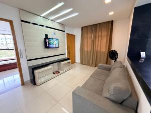 a living room with a couch and a flat screen tv at Apartamento 4 Quartos Completo UEMG Parque Expô in Divinópolis