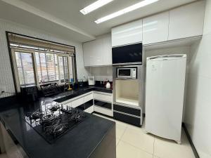a kitchen with white cabinets and a black counter top at Apartamento 4 Quartos Completo UEMG Parque Expô in Divinópolis
