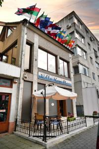 a building with chairs and an umbrella in front of it at Vila Rosa Maria in Mangalia