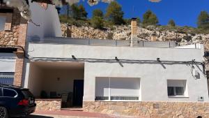 a white house with a car parked in front of it at Mirador de Molinicos in Molinicos