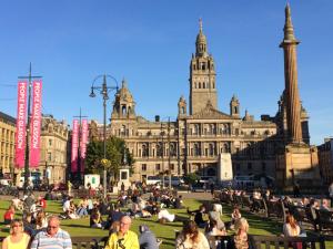 a group of people sitting on benches in front of a building at Glasgow City Center Flat with Parking in Glasgow