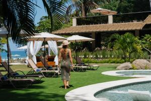 a woman in a dress standing next to a swimming pool at Miamar in Manuel Antonio