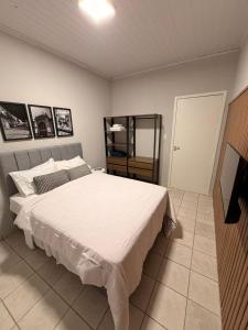 a bedroom with a large white bed and a television at Apart Centro 06 in Tubarão +2 photos