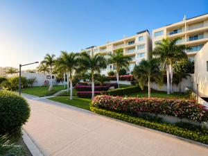 a building with palm trees and flowers in a park at Casa Vista 133 in Cabo San Lucas