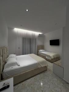 a bedroom with two beds and a flat screen tv at StayVibe in Krujë +5 photos