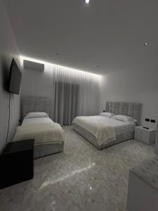 a bedroom with two beds and a television in it at StayVibe in Krujë
