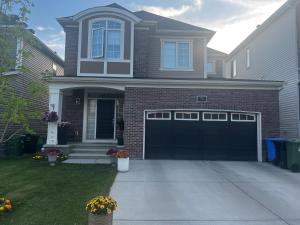 a house with black garage doors in a yard at Cozy private basement suite with separate entrance in Calgary