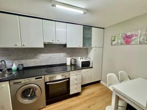 a kitchen with white cabinets and a washer and dryer at Casa A Codela in Combarro