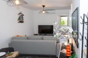 a living room with a couch and a tv at MAISON LEUCATINE - Classée 4 étoiles ! BBQ & Terrasse Privée - Climarisation & Parking privé - Séjour PROCHE PLAGE et IDEAL Famille - OFFRE SPECIALE - in Leucate-Plage +29 photos