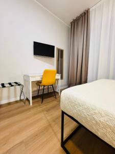 a bedroom with a bed and a desk with a yellow chair at Porta Amari B&B in Palermo