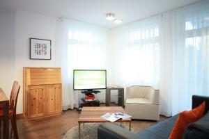ein Wohnzimmer mit einem TV, einem Sofa und einem Tisch in der Unterkunft Ferienwohnung Warnemünde L (S) in Warnemünde
