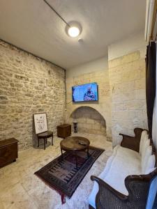 a room with a stone wall with a couch and a table at Antikhan Han Yusufpaşa in Urfa