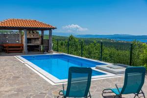 a swimming pool with two chairs and a gazebo at Apartment Panorama in Jadranovo