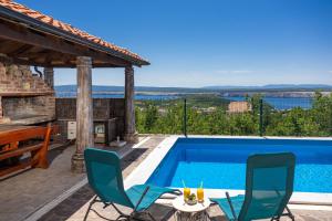 a villa with a swimming pool and two chairs at Apartment Panorama in Jadranovo