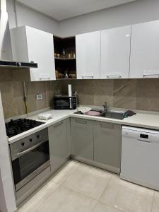 a kitchen with white cabinets and a sink and a stove at Zaineb in Hammamet Sud +10 photos