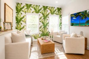 a living room with white furniture and a tropical wallpaper at The Palm Beach House - Tropical in Palm Beach