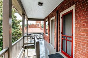 a porch with a red door and a brick building at Red Bud Suite in Staunton