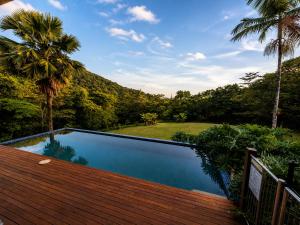 a swimming pool with a wooden deck and palm trees at Cape Tribulation Getaway in Cape Tribulation