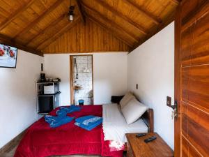 a bedroom with a bed with a red blanket at Chalé Refúgio Jaguary in Monte Verde