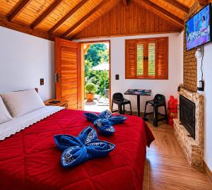 a bedroom with a red bed with blue bows on it at Chalé Refúgio Jaguary in Monte Verde