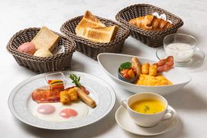 a table with plates of food and baskets of bread at Hotel Bel Air Sendai in Sendai
