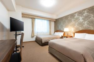 a hotel room with two beds and a flat screen tv at Hotel Bel Air Sendai in Sendai