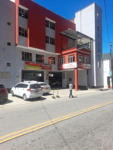a man walking in front of a red and white building at Hotel Cooptmotilon in Pamplona