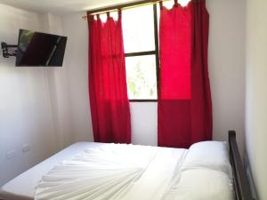 a bedroom with a bed with red curtains and a window at Hotel Cooptmotilon in Pamplona