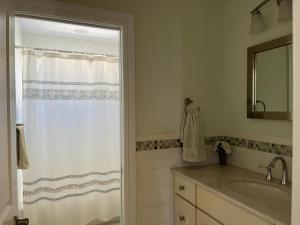 a bathroom with a sink and a shower with a mirror at Bayside Gem in Beach Haven Crest +22 photos