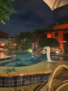 a swimming pool at night with a water slide at Vilarejo do farol in Praia do Forte