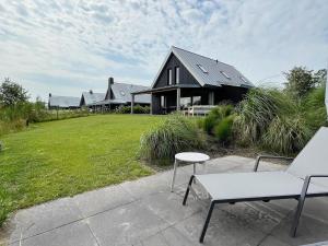 a black house with a lawn and a white chair at Fantastic villa located by a lake in Sint Nicolaasga