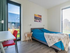 a bedroom with a bed and a desk and a window at Fantastic villa located by a lake in Sint Nicolaasga