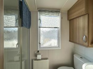 a bathroom with a shower and a toilet and a window at Hamilton Unit 145 in Eyemouth